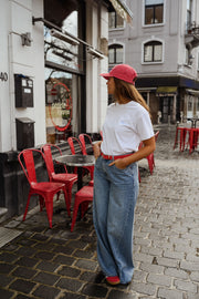 T-shirt à logo cœur dos porté par une femme, silhouette entière, casquette rouge, rue, de loin