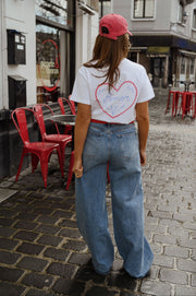 T-shirt à logo cœur dos porté par une femme, vue de dos, casquette rouge, jean large