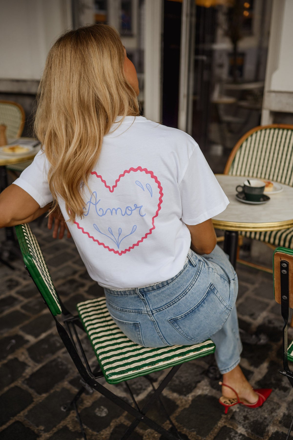 T-shirt à logo cœur dos porté par une femme, assise, logo cœur rose dans le dos