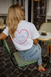 T-shirt à logo cœur dos porté par une femme, assise, logo cœur rose dans le dos