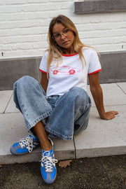 T-shirt ajusté à manches courtes porté par une femme, assise, marche en béton, baskets bleues