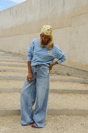 T-shirt rayé à patch porté par une femme, silhouette entière, sur des marches