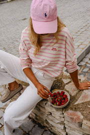 T-shirt rayé à manches longues rose porté par une femme, assise, fraises, casquette rose