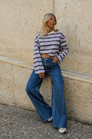 T-shirt rayé manches longues porté par une femme, silhouette entière, adossée à un mur, vue de face