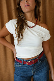 T-shirt moulant asymétrique écru porté par une femme, vue rapprochée, collier rouge