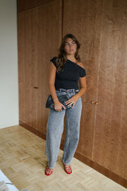 T-shirt moulant asymétrique noir porté par une femme, vue de face, sac à la main, autre cadrage