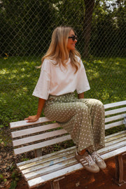 T-shirt épais col rond blanc porté par une femme, assise, banc blanc, pantalon à motifs