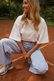 T-shirt épais col rond blanc porté par une femme, assise, court de tennis, baskets