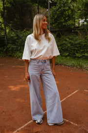 T-shirt épais col rond blanc porté par une femme, vue de face, court de tennis, pantalon large