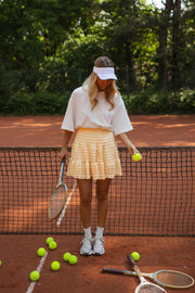 T-shirt épais col rond blanc porté par une femme, vue de face, filet de tennis, jupe jaune