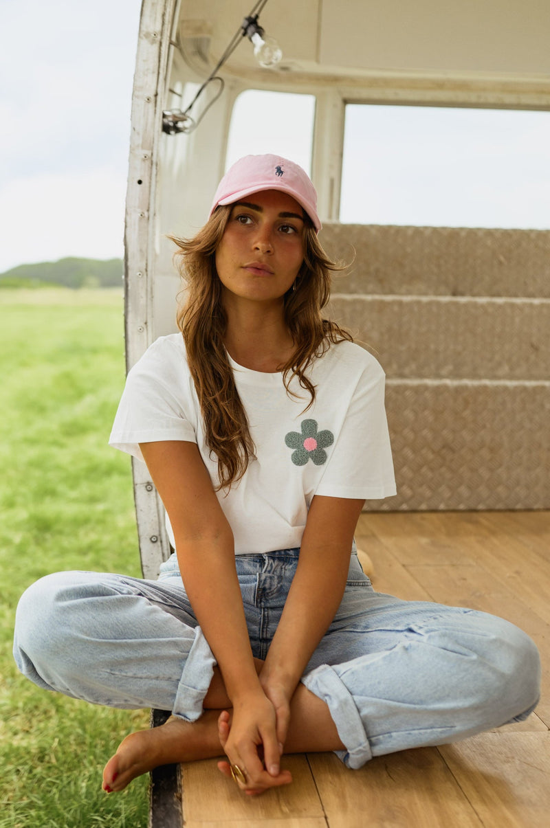 T-shirt à motif floral porté par une femme, assise, au sol, jean
