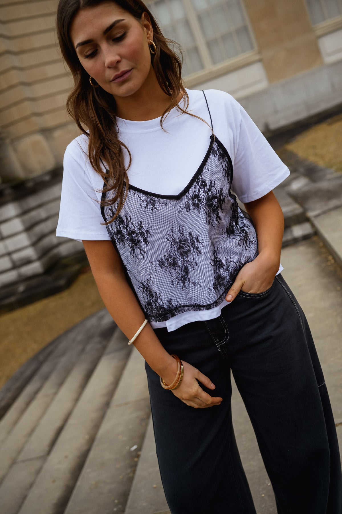 T-shirt à dentelle amovible porté par une femme, vue de trois-quarts, marches, jean noir