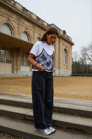 T-shirt à dentelle amovible porté par une femme, vue de face, escalier, jean large noir
