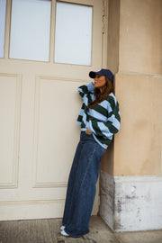 T-shirt ample à larges rayures porté par une femme, vue de trois-quarts, coin de mur, casquette