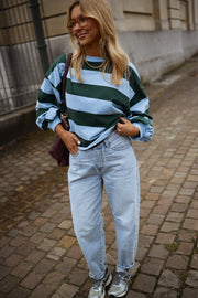 T-shirt ample à larges rayures porté par une femme, vue de face, pavés, jean clair