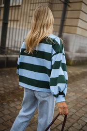 T-shirt ample à larges rayures porté par une femme, vue de dos, pavés, cheveux blonds