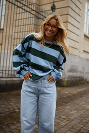 T-shirt ample à larges rayures porté par une femme, vue de face, grille, jean clair