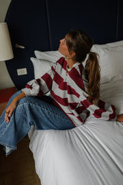 T-shirt rayé ample col rond porté par une femme, allongée sur un lit, queue-de-cheval