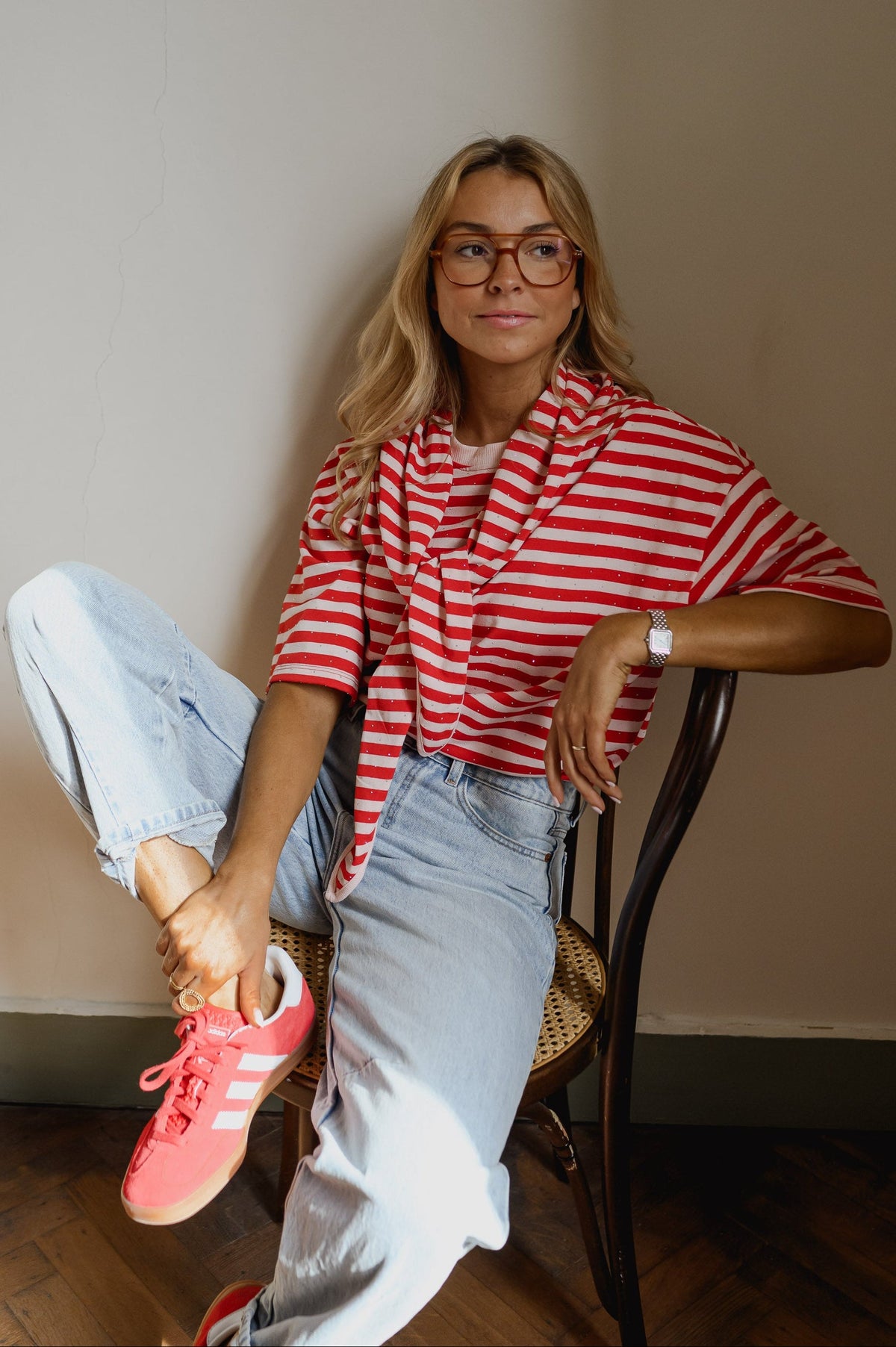 T-shirt à strass avec foulard porté par une femme, assise, sur une chaise, baskets roses