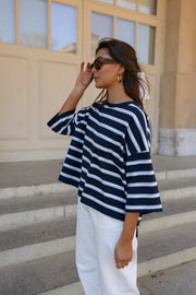 T-shirt rayé à dos ouvert porté par une femme, vue de trois-quarts, lunettes de soleil, sur des marches