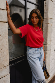 T-shirt ample à manches courtes rouge porté par une femme, vue de trois-quarts, bras levé, jean clair