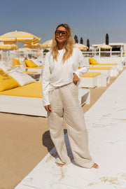 T-shirt doux à manches longues blanc porté par une femme, vue de face, plage, transats jaunes