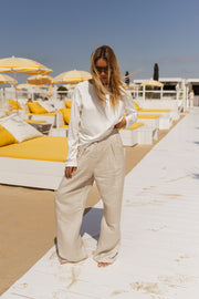 T-shirt doux à manches longues blanc porté par une femme, vue de face, plage, pantalon beige