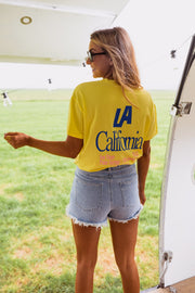 T-shirt à logo recto verso porté par une femme, vue de trois-quarts, short en jean, caravane