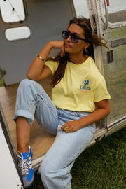T-shirt à logo recto verso porté par une femme, assise, jean clair, caravane