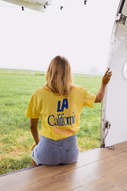 T-shirt à logo recto verso porté par une femme, assise, de dos, caravane