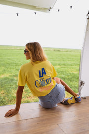 T-shirt à logo recto verso porté par une femme, assise, sol, short en jean