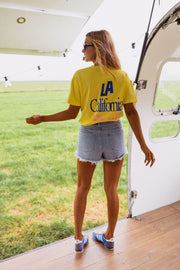 T-shirt à logo recto verso porté par une femme, silhouette entière, short en jean, caravane