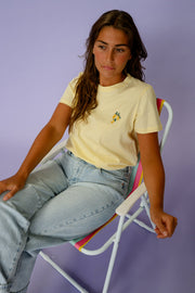 T-shirt à logo citron porté par une femme, assise, sur une chaise de plage, de côté