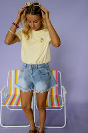 T-shirt à logo citron porté par une femme, vue rapprochée, mains dans les cheveux