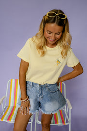 T-shirt à logo citron porté par une femme, vue rapprochée, lunettes de soleil sur la tête, mains dans les poches