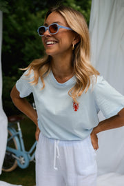 T-shirt homard brodé porté par une femme, vue rapprochée, sourire, lunettes