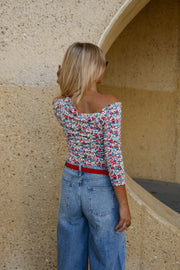 T-shirt fleuri asymétrique moulant porté par une femme, vue de dos