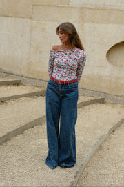 T-shirt fleuri asymétrique moulant porté par une femme, silhouette entière, sur des gradins