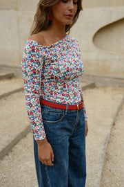T-shirt fleuri asymétrique moulant porté par une femme, vue rapprochée, ceinture rouge