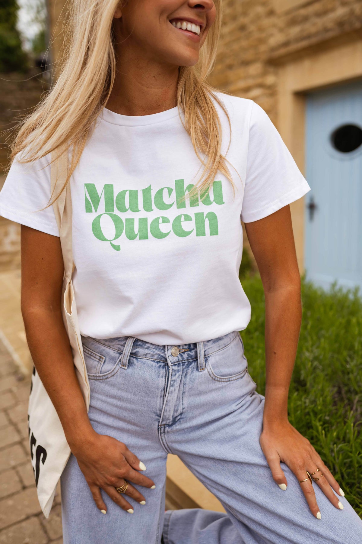 T-shirt blanc à logo vert porté par une femme, vue rapprochée, inscription verte, jean