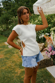 T-shirt à perles latérales porté par une femme, vue de trois-quarts, main levée, jardin