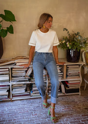 T-shirt épais brodé aux manches porté par une femme, silhouette entière, jean, plantes