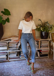 T-shirt épais brodé aux manches porté par une femme, silhouette entière, jean, de loin, sandales vertes