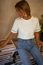T-shirt épais brodé aux manches porté par une femme, vue de trois-quarts, jean, livres