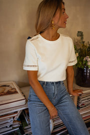 T-shirt épais brodé aux manches porté par une femme, vue de trois-quarts, jean, bibliothèque