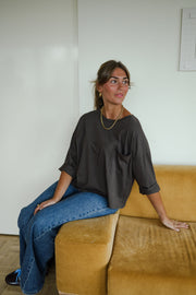 T-shirt ample à poche poitrine porté par une femme, assise, sur un canapé, de côté