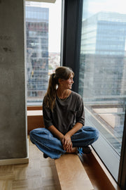 T-shirt ample à poche poitrine porté par une femme, assise, sur un banc, jambes croisées