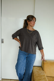 T-shirt ample à poche poitrine porté par une femme, vue rapprochée, main sur la hanche