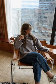 T-shirt loose à col rond porté par une femme, assise, sur une chaise, lunettes de soleil