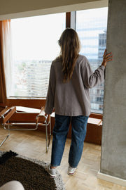 T-shirt loose à col rond porté par une femme, vue de dos, près d'un pilier